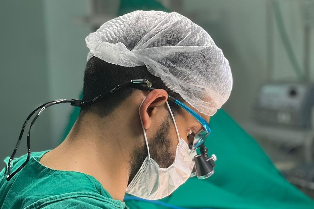Dr. Rodrigo Barros em cirurgia, usando lupa cirúrgica para microcirurgia